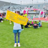 10kmマラソンを完走したスタッフがゴール地点で達成感に満ちた笑顔を見せている様子